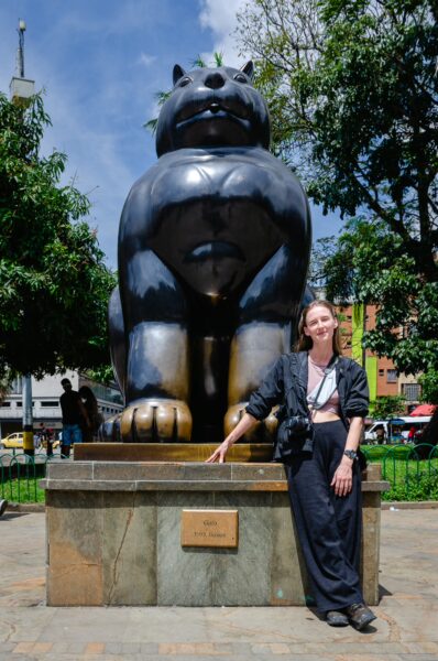 Woman posing beside the Gato sculpture in Plaza Botero, Medellín