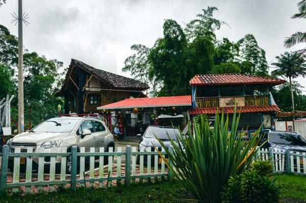 Quaint houses with colorful roofs surrounded by lush greenery and parked cars in Salento, Quindío, Colombia.