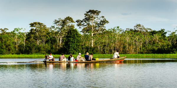 Boaters navigate the calm waters of Pirana Lake, surrounded by lush greenery in Gamboa Nature Reserve, Loreto, Peru.