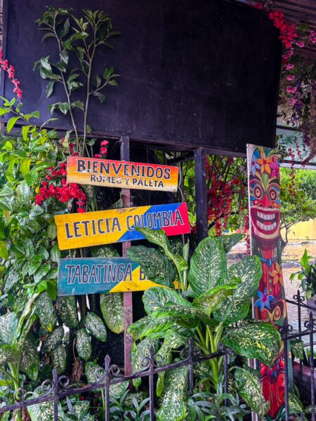 Vibrant signage welcomes visitors to Leticia, Colombia, surrounded by lush greenery and colorful decorations.