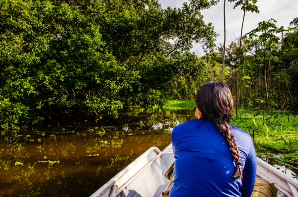 Exploring Gamboa Nature Reserve in Loreto, Peru, a visitor sits on a boat, surrounded by lush green vegetation and calm waters.