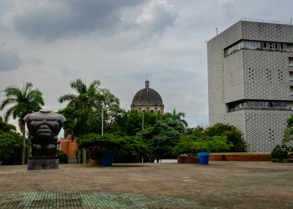 Botero sculpture in Parque de San Antonio with San Antonio Church and a patterned modern building in Medellín