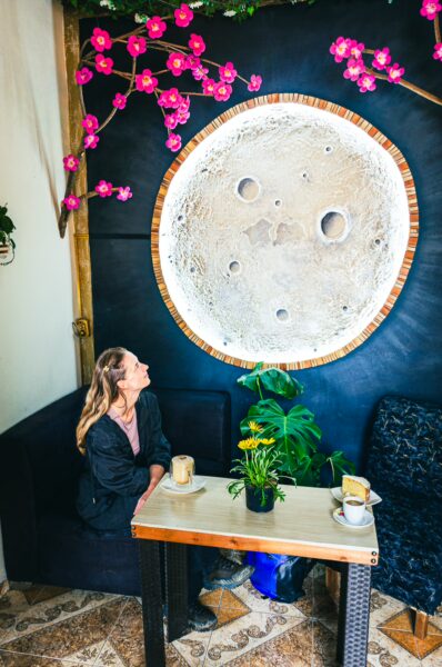 Skywind Café features a vibrant interior with pink flowers, a moon mural, and a cozy seating area in Salento, Quindío, Colombia.