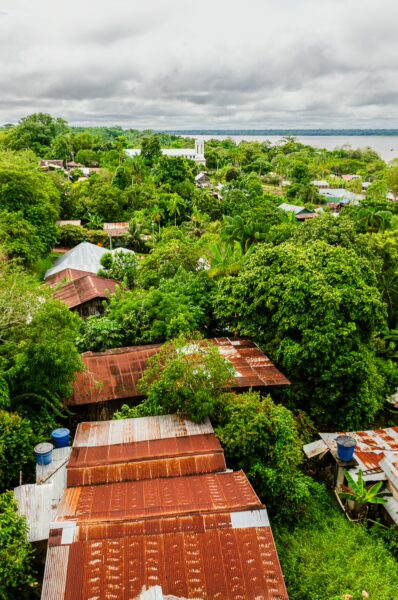 Lush greenery envelops rust-colored roofs in Puerto Nariño, Amazonas, Colombia, showcasing the vibrant landscape and local architecture.