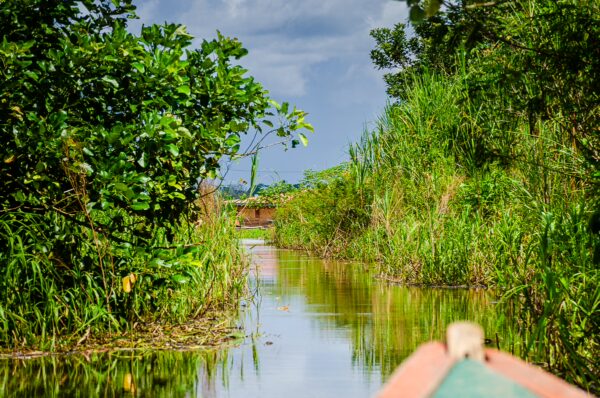Lush green vegetation flanks a tranquil waterway in Santa Rosa, Amazonas, with reflections shimmering on the calm surface.