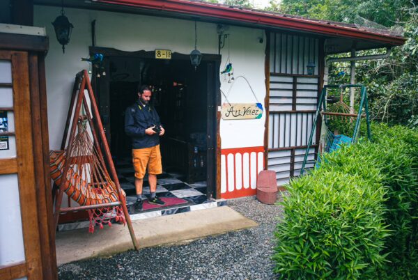 Vibrant entrance of a traditional house in Velez Salento, Quindio, with a person standing under a red-roofed porch.