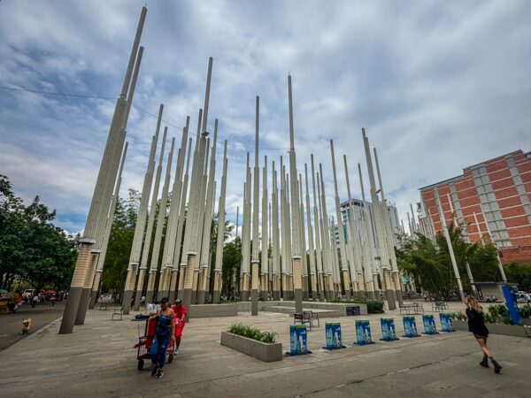 Parque de Las Luces in Medellín, with tall light towers rising over an open plaza and a few people walking across the concrete space