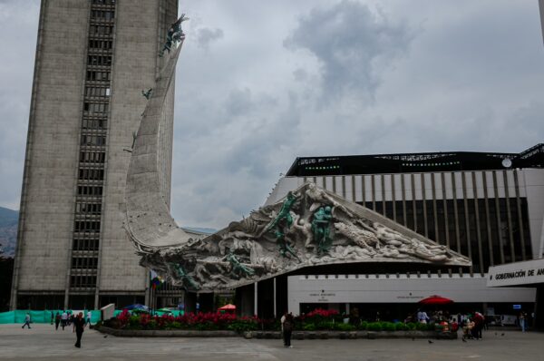 Monumento a la Raza sculpture in central Medellín beside government buildings under a cloudy sky