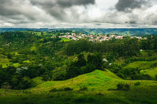 Lush green hills and valleys surround the quaint town of Salento, Quindío, under a cloudy sky. Scenic landscape captures Colombia's beauty.