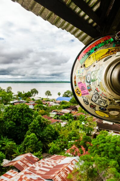 Colorful stickers on a lamp highlight the lush greenery and rooftops of Puerto Nariño by the Amazonas River in Colombia.