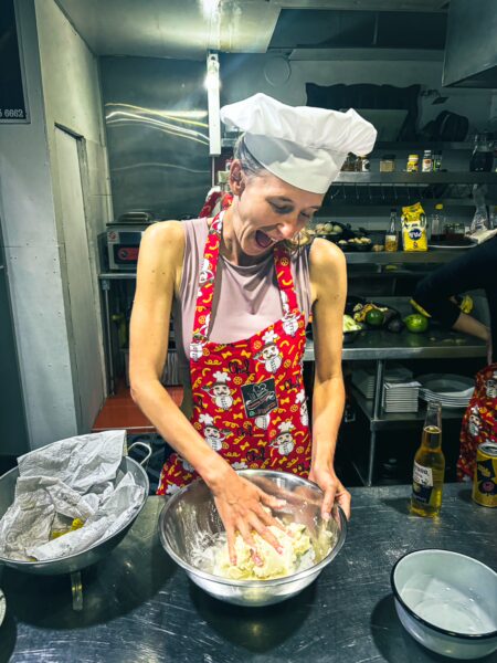 Enthusiastic participant mixing dough in a vibrant apron during a cooking class in Salento, Quindio, Colombia.