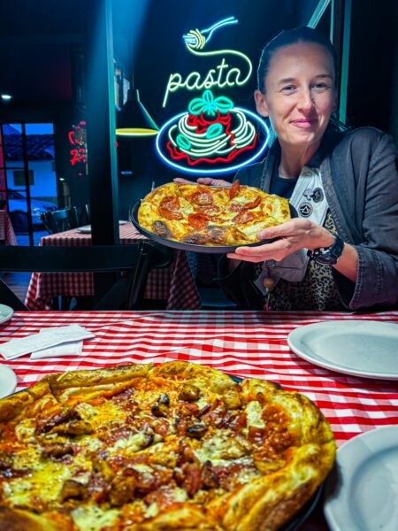 Delicious pizza with toppings in front of a woman, set on a checkered tablecloth at a vibrant pasta restaurant in Salento, Colombia.