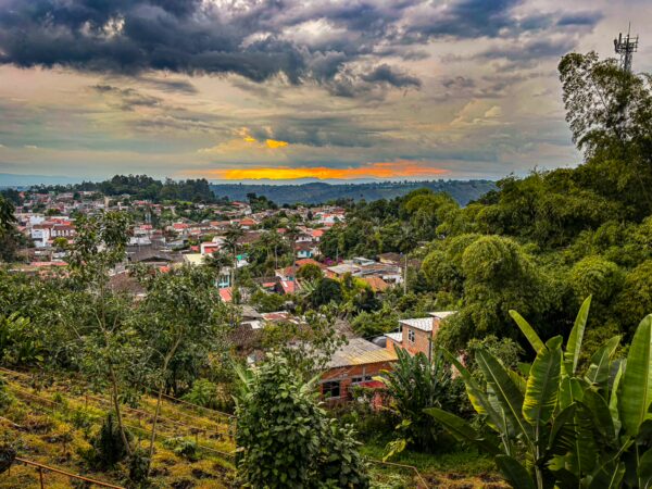 Vibrant sunset casts a warm glow over the lush hills and colorful houses of Salento, Quindío, Colombia.