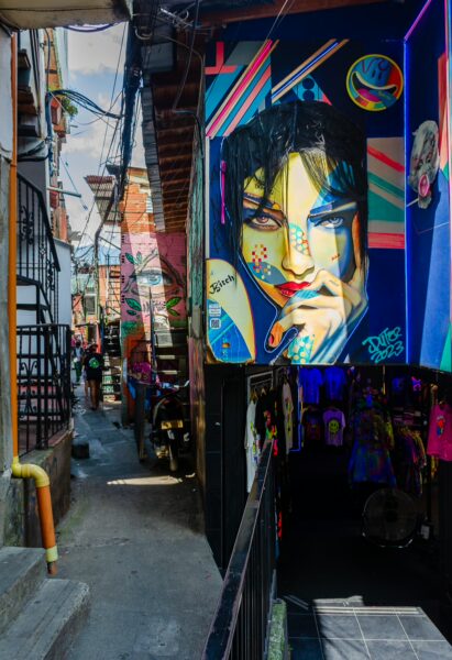 Vibrant street art adorns the walls of Comuna 13 in Medellín, featuring bold colors and intricate designs in a lively alley.