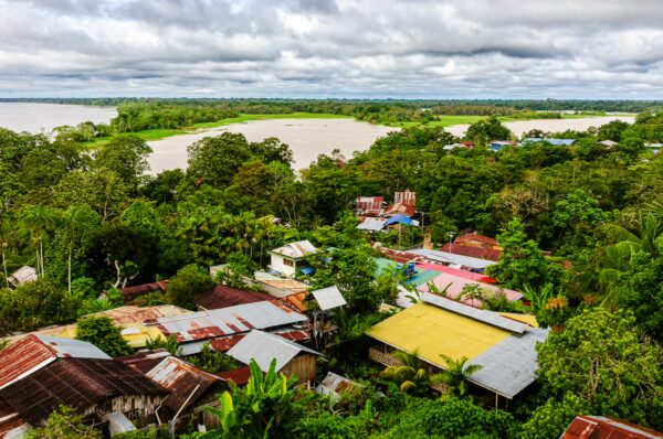 Vibrant rooftops and lush greenery overlook the vast Amazon River, showcasing the natural beauty of Puerto Nariño, Amazonas, Colombia.