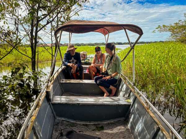 Three people relax in a boat surrounded by lush green vegetation at Pirana Lake in Gamboa Nature Reserve, Loreto, Peru.