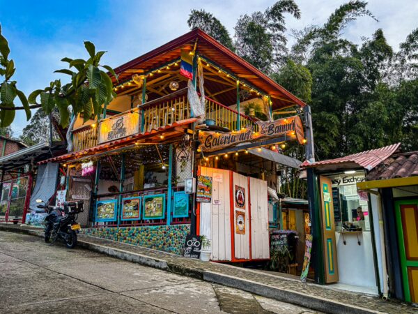Colorful café with bright lights nestled in a hillside in Salento, Quindío, Colombia, surrounded by lush greenery.