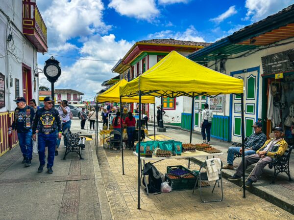 Vibrant street scene along Calle Real in Salento, Quindío, Colombia, featuring colorful tents, local vendors, and lively pedestrians.