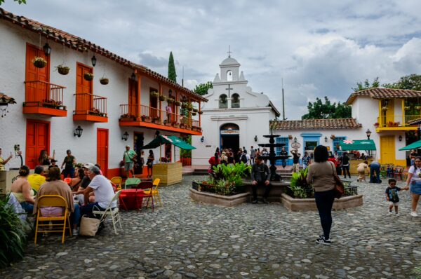 Cobblestone plaza at Pueblito Paisa in Medellín, with colorful colonial-style buildings and a small white church