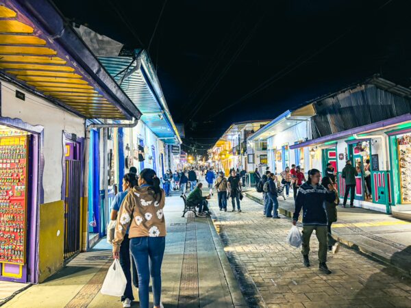 Lively Calle Real in Salento, Quindío, Colombia, features colorful shops and bustling crowds under night lights.