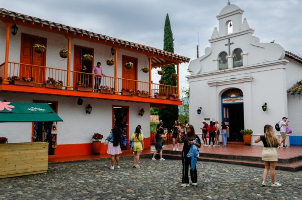 Cobblestone plaza in Pueblito Paisa with a white church and orange-trimmed balcony buildings