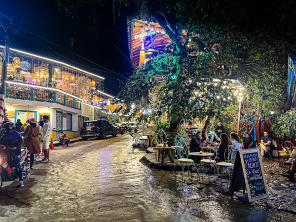 Colorful lights illuminate Calle Real in Salento, Quindío, Colombia, as visitors enjoy vibrant cafes and lively street scenes at night.
