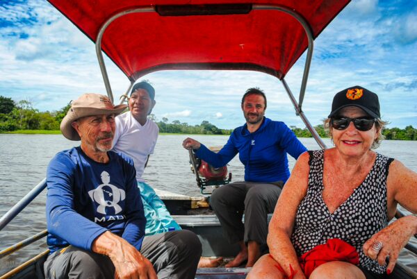 Relaxing on a boat in Pirana Lake, Gamboa Nature Reserve, with lush greenery and blue skies in Loreto, Peru.