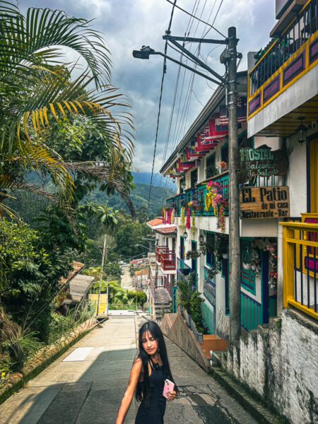 Vibrant streets of Salento, Quindio, Colombia, lined with colorful buildings and lush greenery under a cloudy sky.