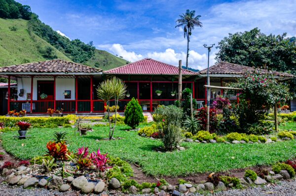 Vibrant gardens surround traditional houses with red roofs at Santa Rita Waterfalls, Salento, Quindío, Colombia.