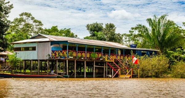 Colorful stilt house in Gamboa Nature Reserve, reflecting vibrant local culture against lush greenery and tranquil waters in Loreto, Peru.