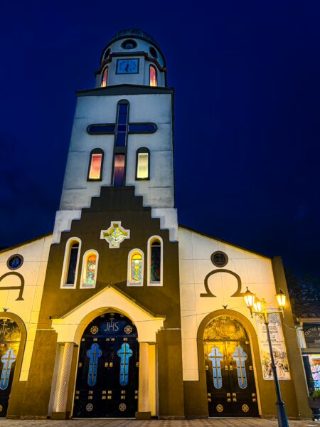 Nuestra Señora de Carmen glows at night in Salento, Quindío, with vibrant stained glass and distinctive architectural features.