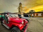 Bright red Willys jeep parked in front of a charming colonial building during sunset in Salento, Quindio, Colombia.