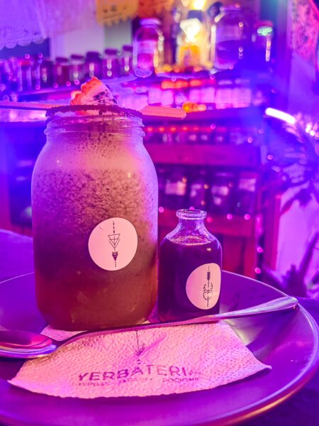 Refreshing yerba mate served in a glass jar with a small bottle on a plate at Bumi Cocina Natural in Salento, Quindio, Colombia.