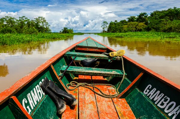 Brightly colored wooden boat in Gamboa Nature Reserve, surrounded by lush greenery and calm waters in Loreto, Peru.
