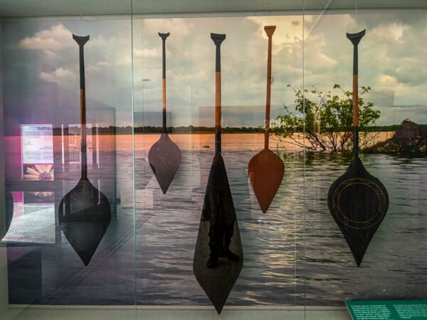 Traditional paddles displayed against a backdrop of the Amazon River's sunset at the ethnographic museum in Leticia, Amazonas, Colombia.