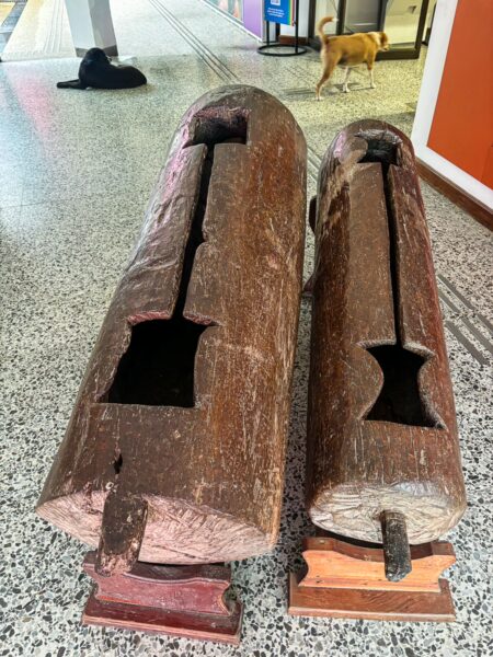 Wooden artifacts displayed in the Ethnographic Museum, Leticia, Amazonas, Colombia, with a dog visible in the background.