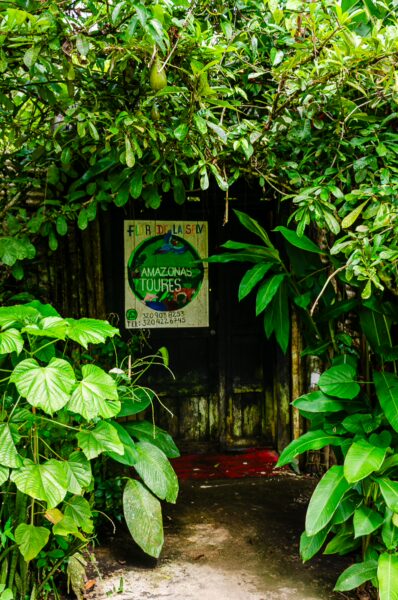 Vibrant green foliage frames a rustic entrance to a building in Puerto Nariño, Amazonas, Colombia, highlighting local nature.