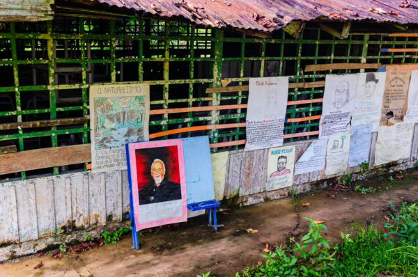 Vibrant posters and a colorful portrait adorn the walls of a rustic building in Puerto Nariño, Amazonas, Colombia.