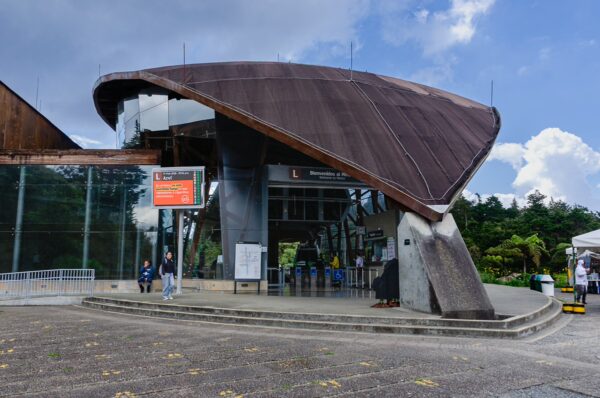 Modern architecture of the Arví Park entrance in Medellín, featuring a unique roof design and lush greenery surrounding it.