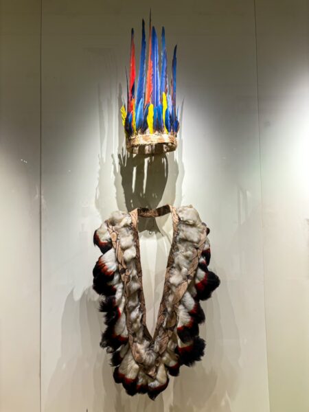 Vibrant feathered headdress and traditional necklace on display at the ethnographic museum in Leticia, Amazonas, Colombia.