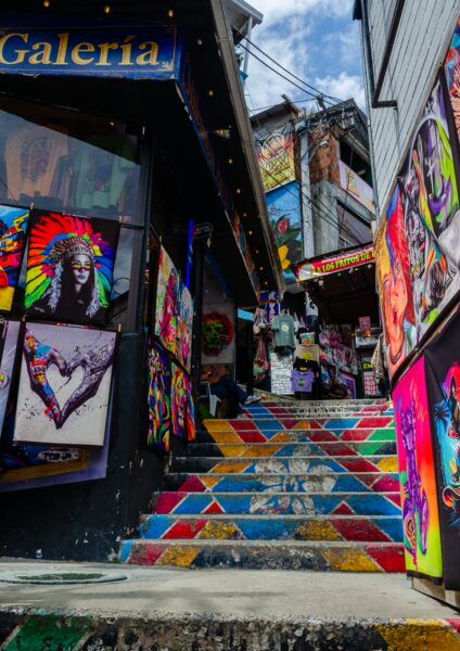 Vibrant street art and colorful stairs lead up through Comuna 13, Medellín, showcasing local culture and creativity.
