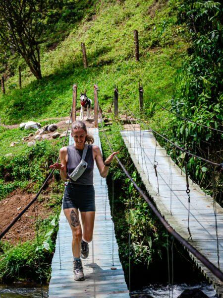 A traveler crosses a suspension bridge surrounded by lush greenery near the Santa Rita Waterfalls in Salento, Quindio, Colombia.