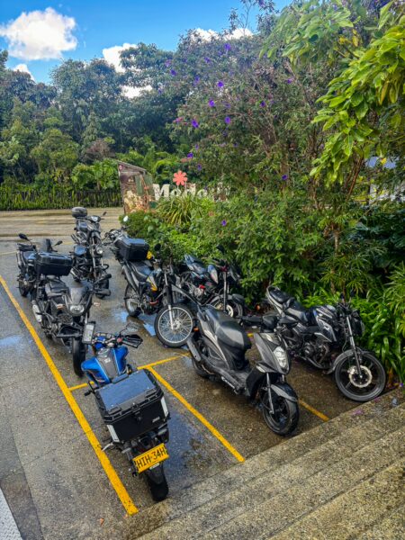 Motorcycles parked near lush greenery at Arvi Park in Medellín, Antioquia, Colombia, showcasing a vibrant outdoor atmosphere.