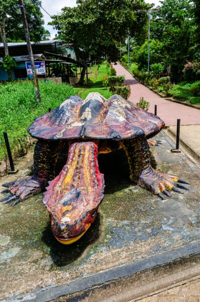 Colorful sculpture of a large turtle in Puerto Narino, Amazonas, Colombia, surrounded by lush greenery and a pathway.
