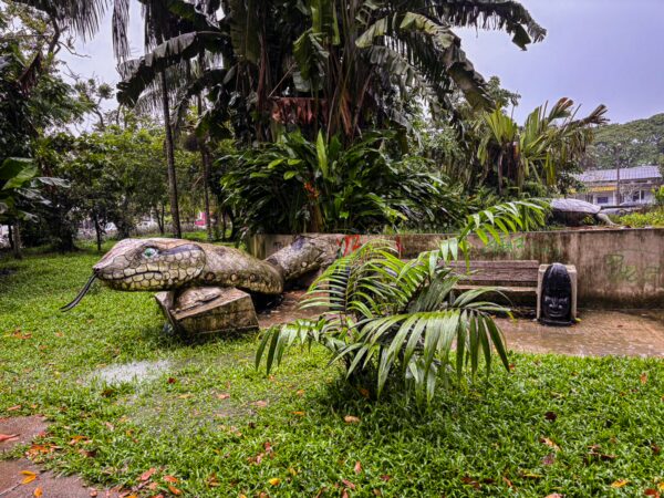 Large snake sculpture surrounded by lush greenery in Parque Santander, Leticia, Amazonas, Colombia.