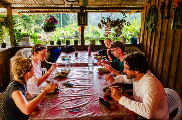 Dining at El Gallego in Carbonera Valley, Quindio, Colombia, guests enjoy local cuisine surrounded by lush greenery and vibrant flowers.