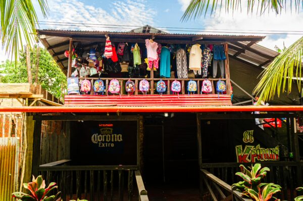 Vibrant shopfront in Puerto Narino, Amazonas, Colombia, featuring colorful clothing and local artworks under a clear blue sky.