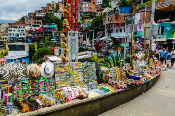 Vibrant stall filled with handmade crafts and souvenirs in Comuna 13, Medellín, showcasing colorful local culture and architecture.