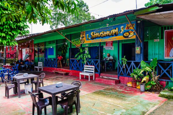 Colorful buildings with vibrant signage and outdoor seating create a lively atmosphere in Puerto Narino, Amazonas, Colombia.