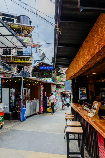 Vibrant streets of Comuna 13 in Medellín, showcasing colorful murals, lively vendors, and a welcoming atmosphere.